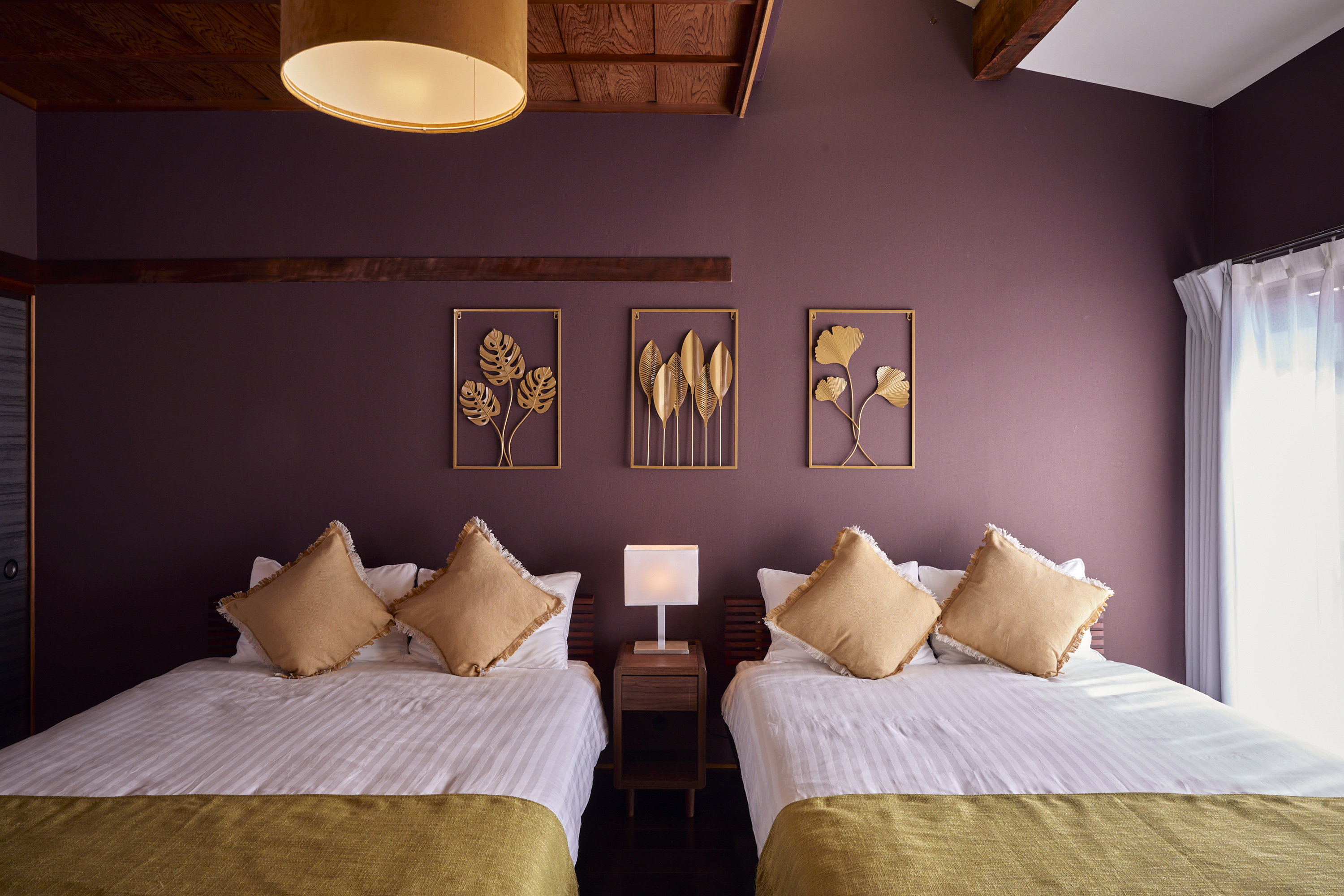 寝室1。深みのあるパープルの壁と金色のボタニカルアート装飾、ツインベッド