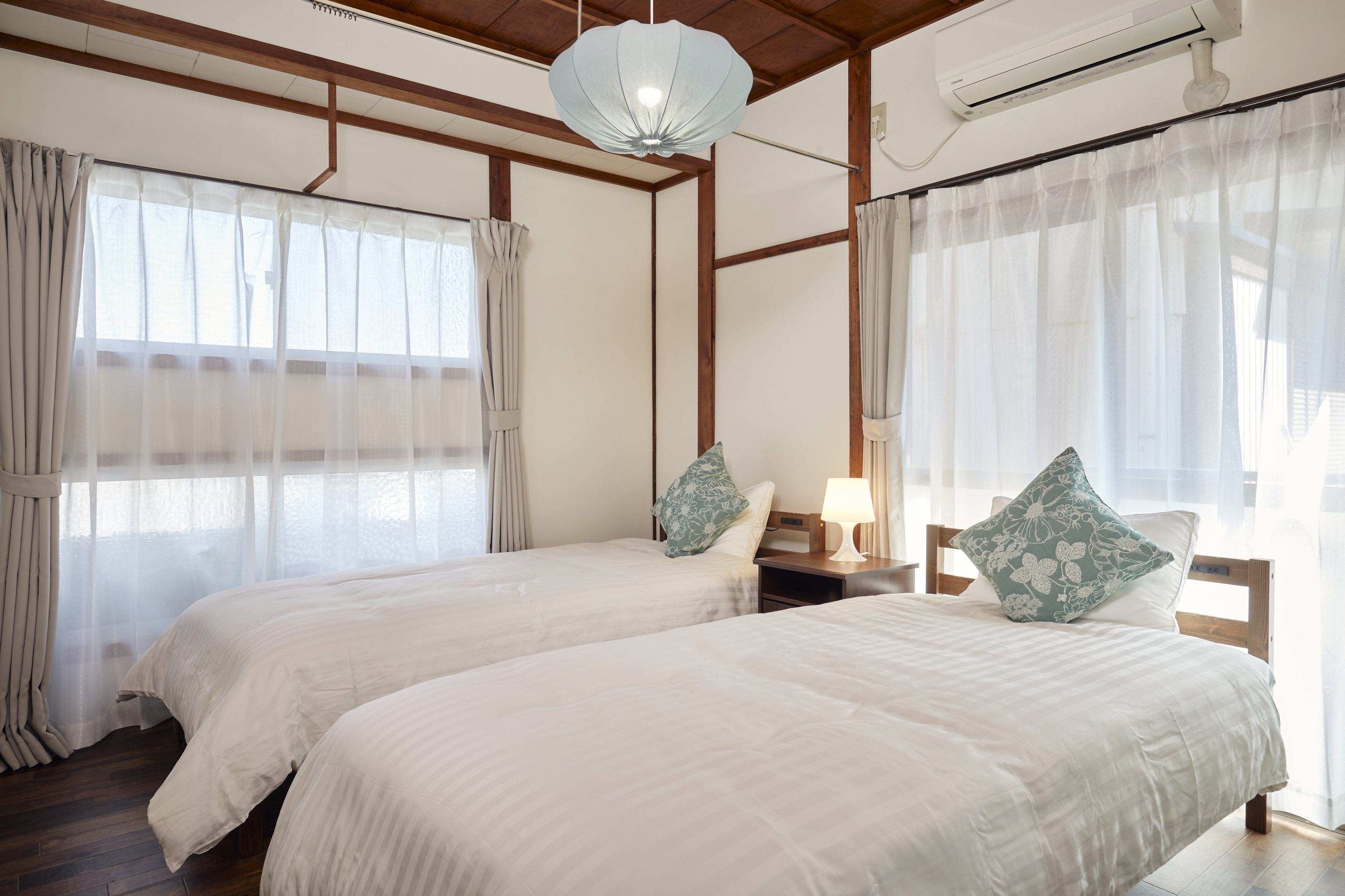 寝室2。伝統的な和室。障子と金彩の描かれた襖、白い寝具とピンクのアクセント