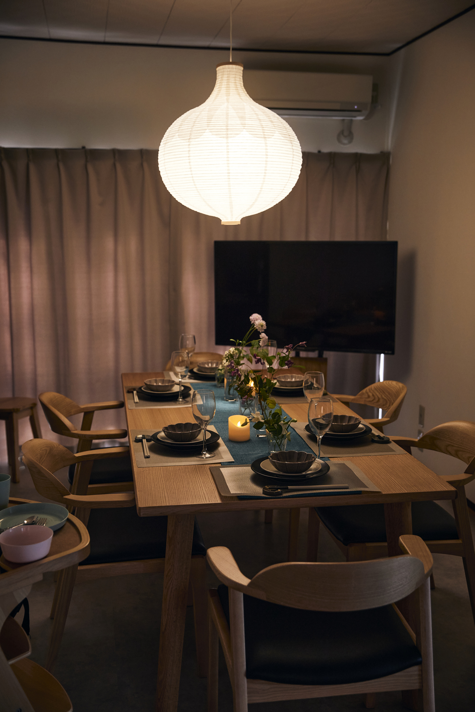 夜のダイニングルーム。和紙のペンダントランプが灯る8人掛けテーブル