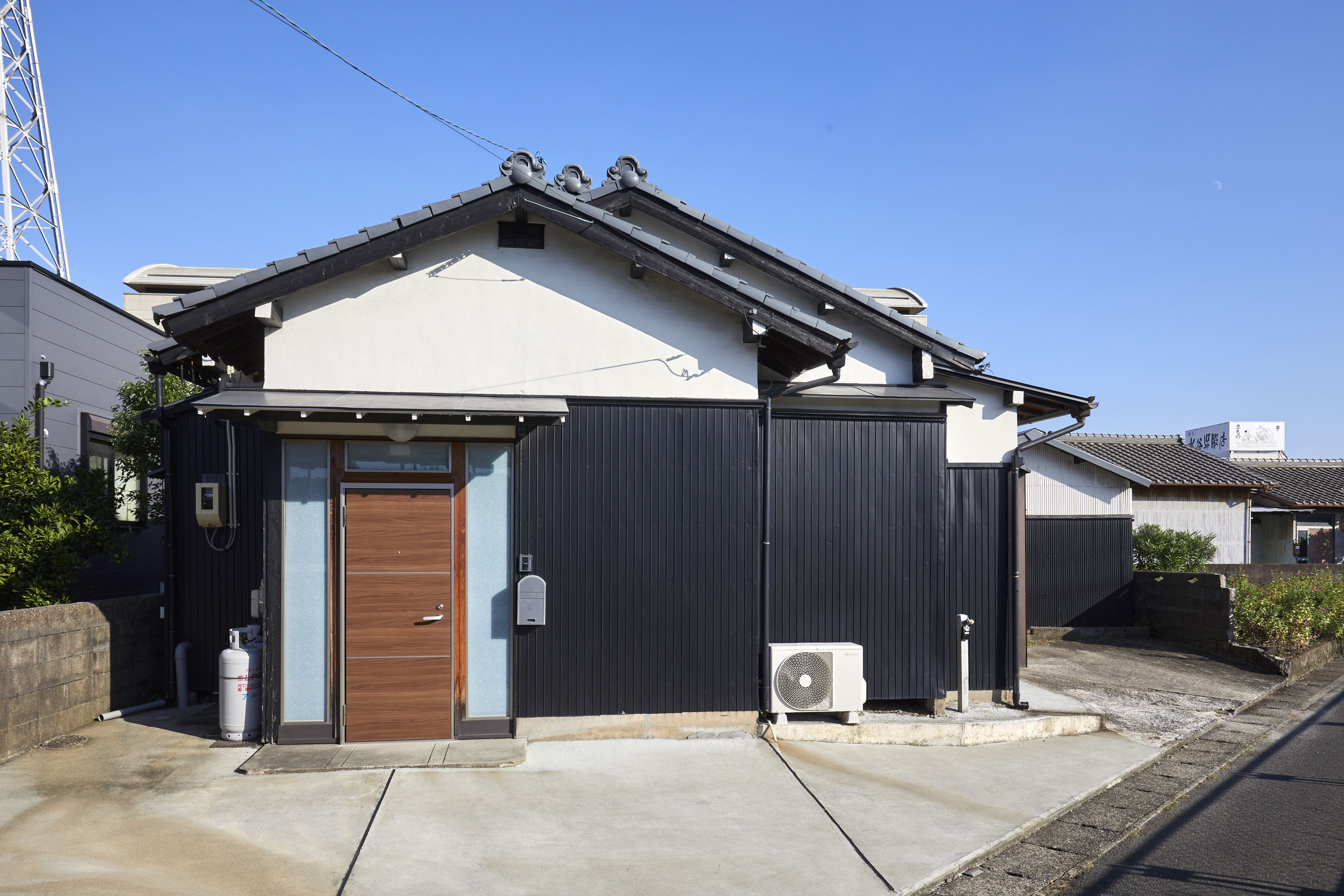 百の宿の外観。伝統的な瓦屋根と黒いガルバリウム外壁、木製の玄関扉